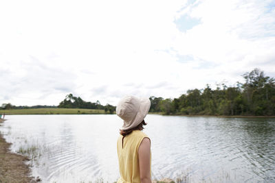 Rear view of woman looking at lake against sky