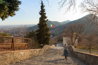 Rear view of man standing on mountain against sky