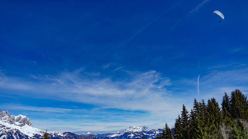 Low angle view of snowcapped mountains against blue sky
