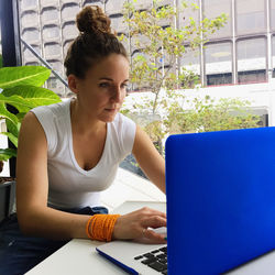 Concentrated woman using laptop by glass window