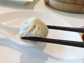 Close-up of chopsticks holding dumpling over plate
