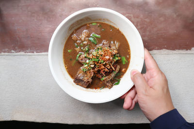 Close-up of hand holding bowl of soup