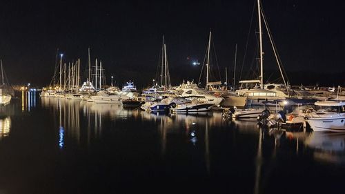 Sailboats moored in harbor at night