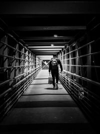 Rear view of man walking on covered bridge