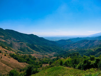 Scenic view of landscape and mountains against blue sky