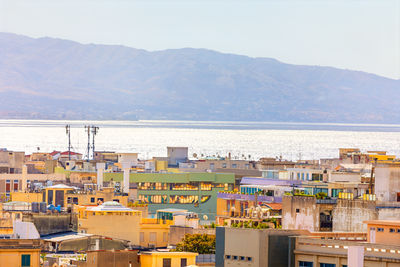 High angle view of townscape by sea against mountains