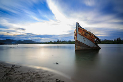 Abandoned boat in lake against sky