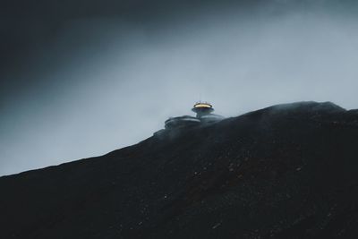 Low angle view of man standing on mountain against sky