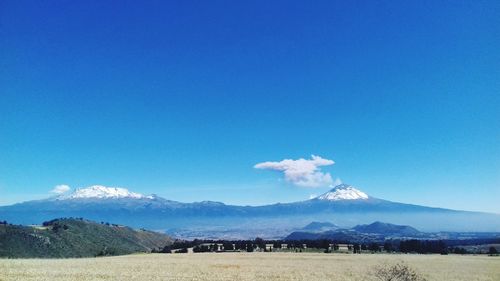 Scenic view of landscape and mountains against blue sky