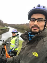 Portrait of smiling man standing by river against clear sky