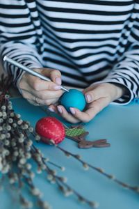 Midsection of person hands painting eggs on table