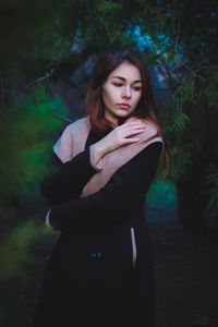 Thoughtful young woman standing in forest