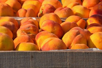 Close-up of peach fruits in wooden crate for sale at market