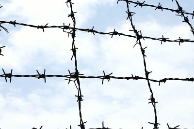 Low angle view of barbed wire against sky