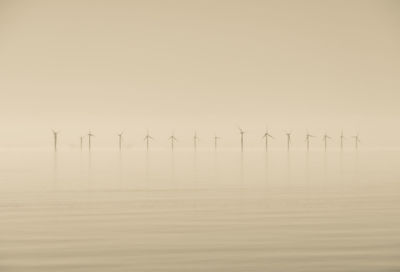 Offshore wind turbines generating renewable electricity and energy  atmospheric background image