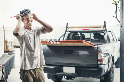 Happy carpenter standing by pick-up truck outside workshop