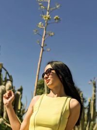 Young woman wearing sunglasses against clear sky