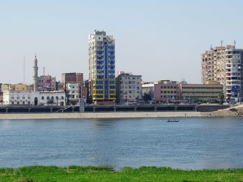 Buildings by river against clear sky