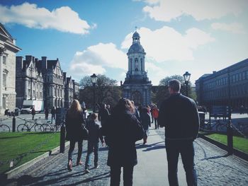 Woman standing on city street against cloudy sky