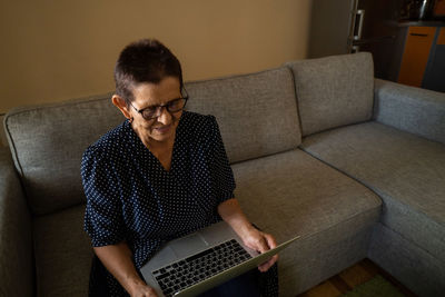 Young man using mobile phone while sitting on sofa