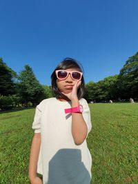 Portrait of girl wearing sunglasses standing on field