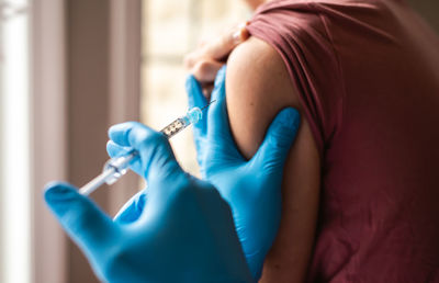 Close up of teen boy getting vaccinated by doctor holding a needle.