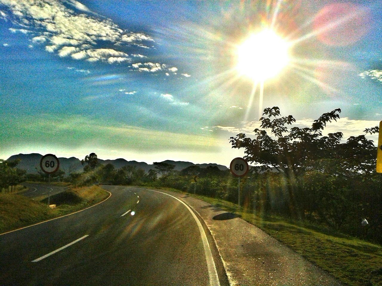 transportation, road, sky, the way forward, sun, cloud - sky, diminishing perspective, vanishing point, landscape, sunlight, blue, road marking, lens flare, country road, tree, street, sunbeam, field, nature, tranquility