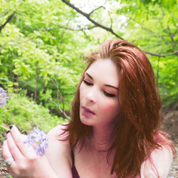 Portrait of beautiful young woman against plants