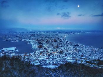 Aerial view of city by sea against sky