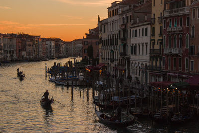 Gondolas on canal in city during sunset