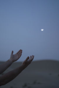Person hand against moon in sky