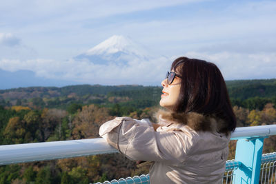 Side view of young woman in mountains against sky