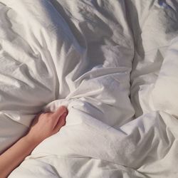 Cropped hand of person relaxing on bed
