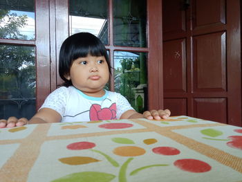 Portrait of cute baby girl on table at home