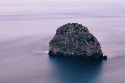 Rock formation in sea against sky