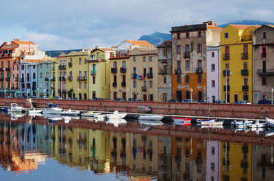 Sailboats moored on canal amidst buildings in city