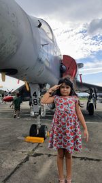 Full length of girl gesturing while standing by airplane