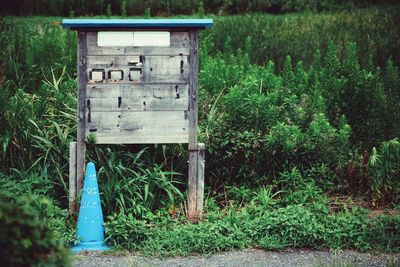 Weathered wooden structure by blue traffic cone on field