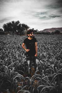 Full length of young man standing on land against sky