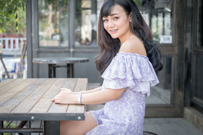 Young woman sitting on wooden table