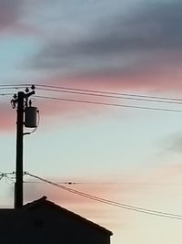 Low angle view of silhouette electricity pylon against sky