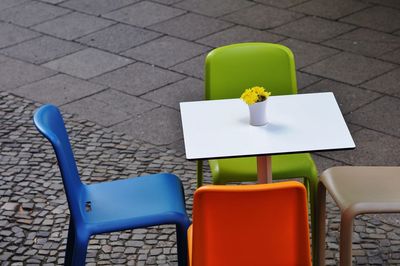 High angle view of empty colorful chairs by table at sidewalk cafe