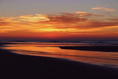 Scenic view of sea against dramatic sky during sunset