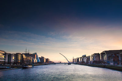 Samuel beckett bridge over river amidst buildings at dusk