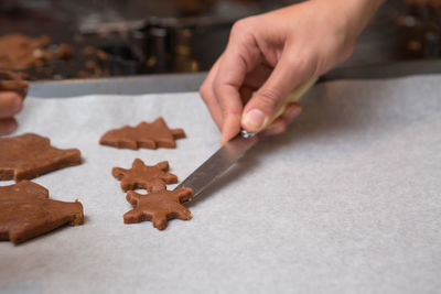 Cropped image of hand holding cookies on table