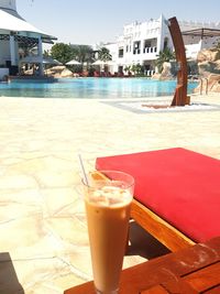 Close-up of drink on table at beach in city against sky