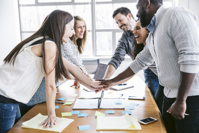 Cheerful business people huddling in meeting at board room