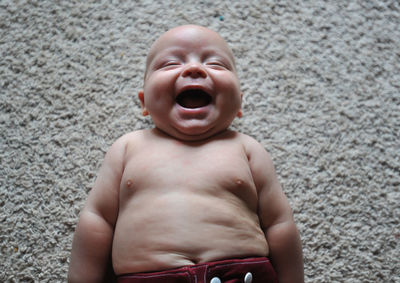 High angle view of cute baby boy laughing while lying on rug