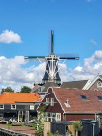 Traditional windmill by building against sky