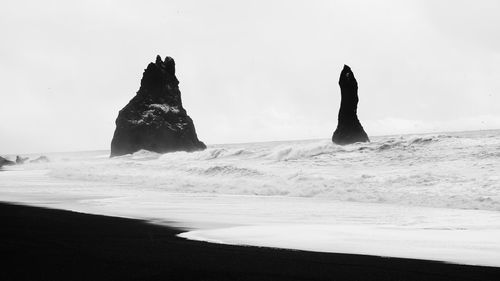 Rocks on beach against clear sky